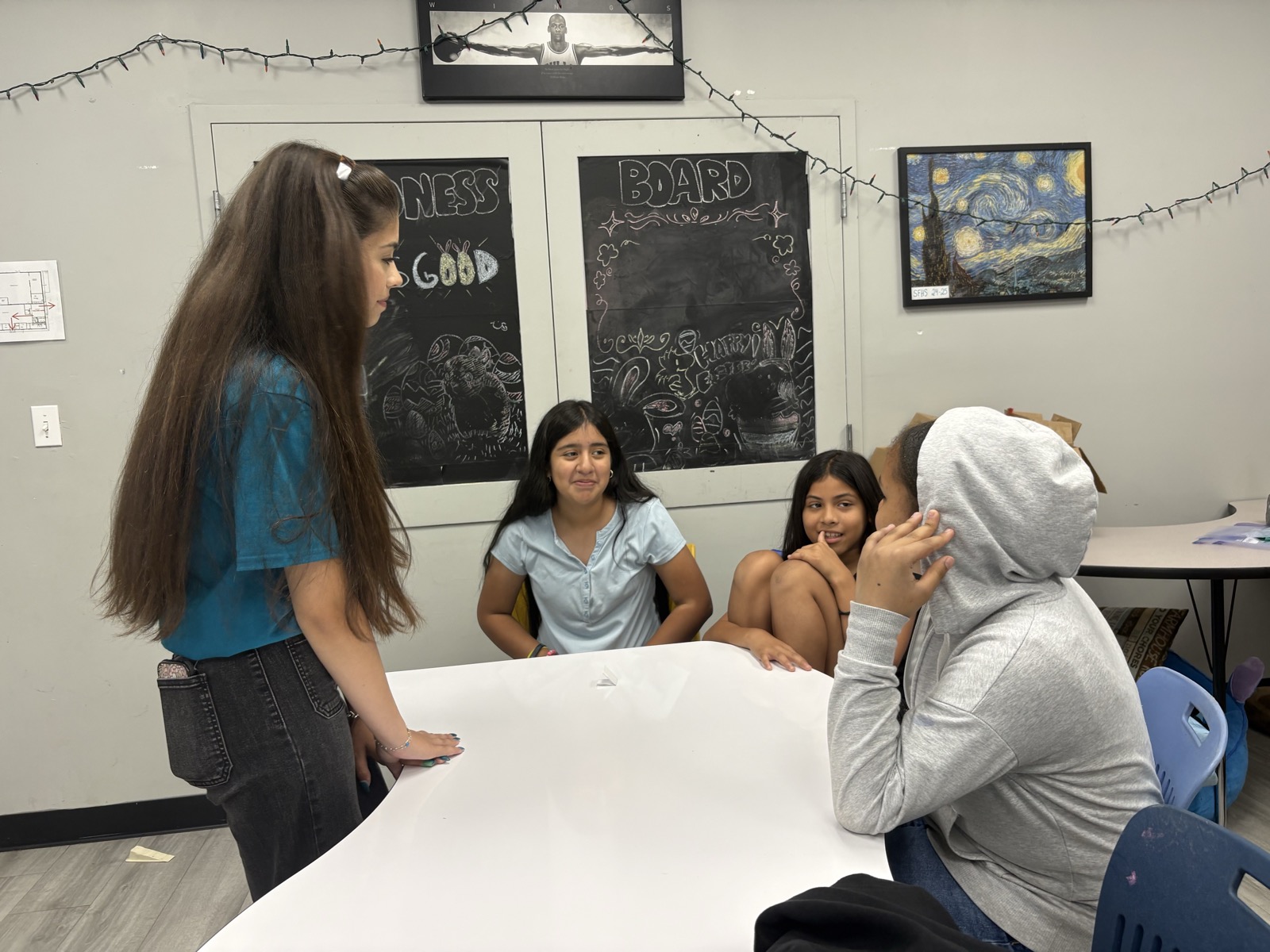 A Speak2Achieve volunteer leading a small group discussion with students seated around a table