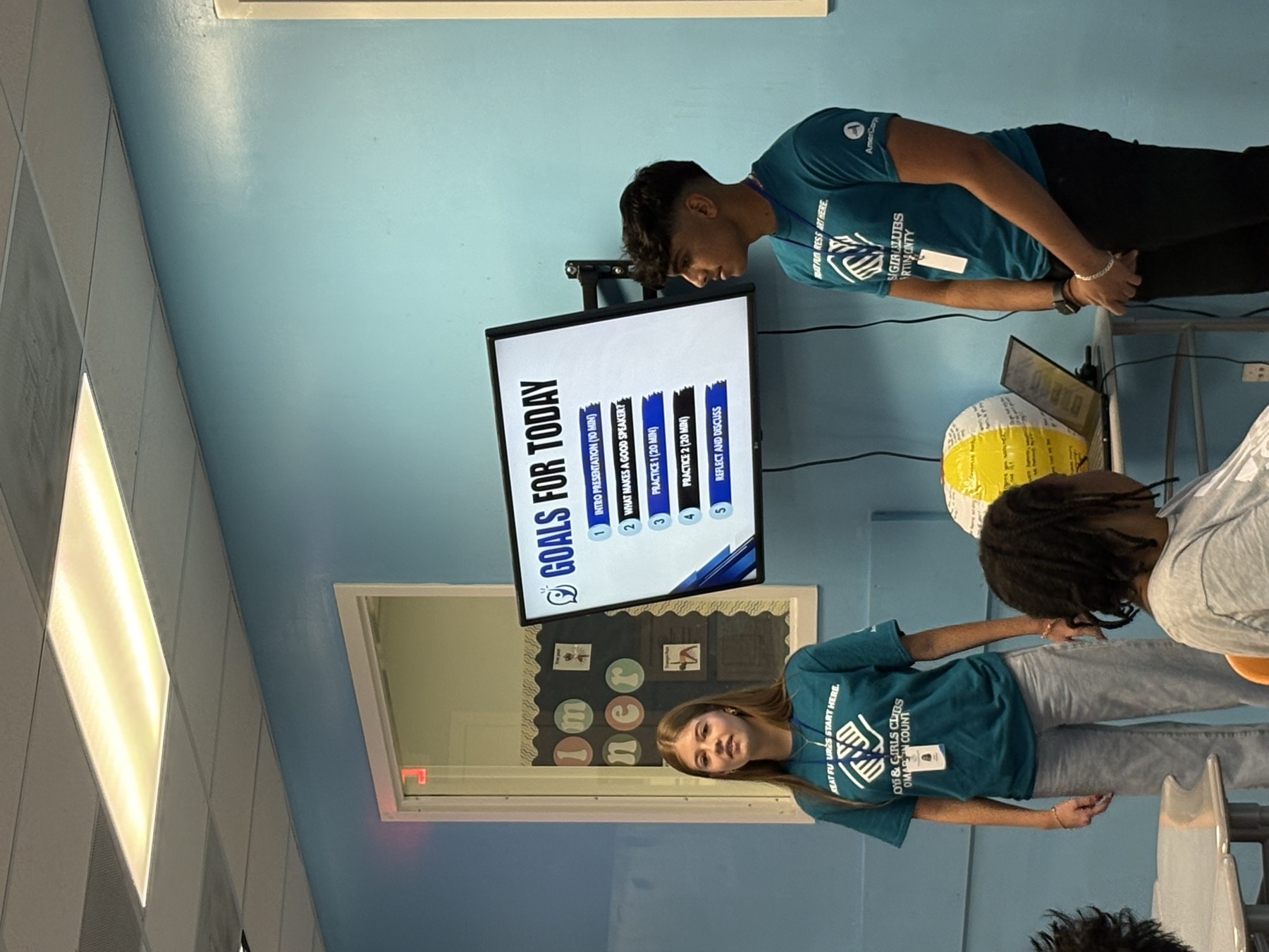 Two Speak2Achieve volunteers presenting the day's goals to students at a Boys & Girls Club workshop