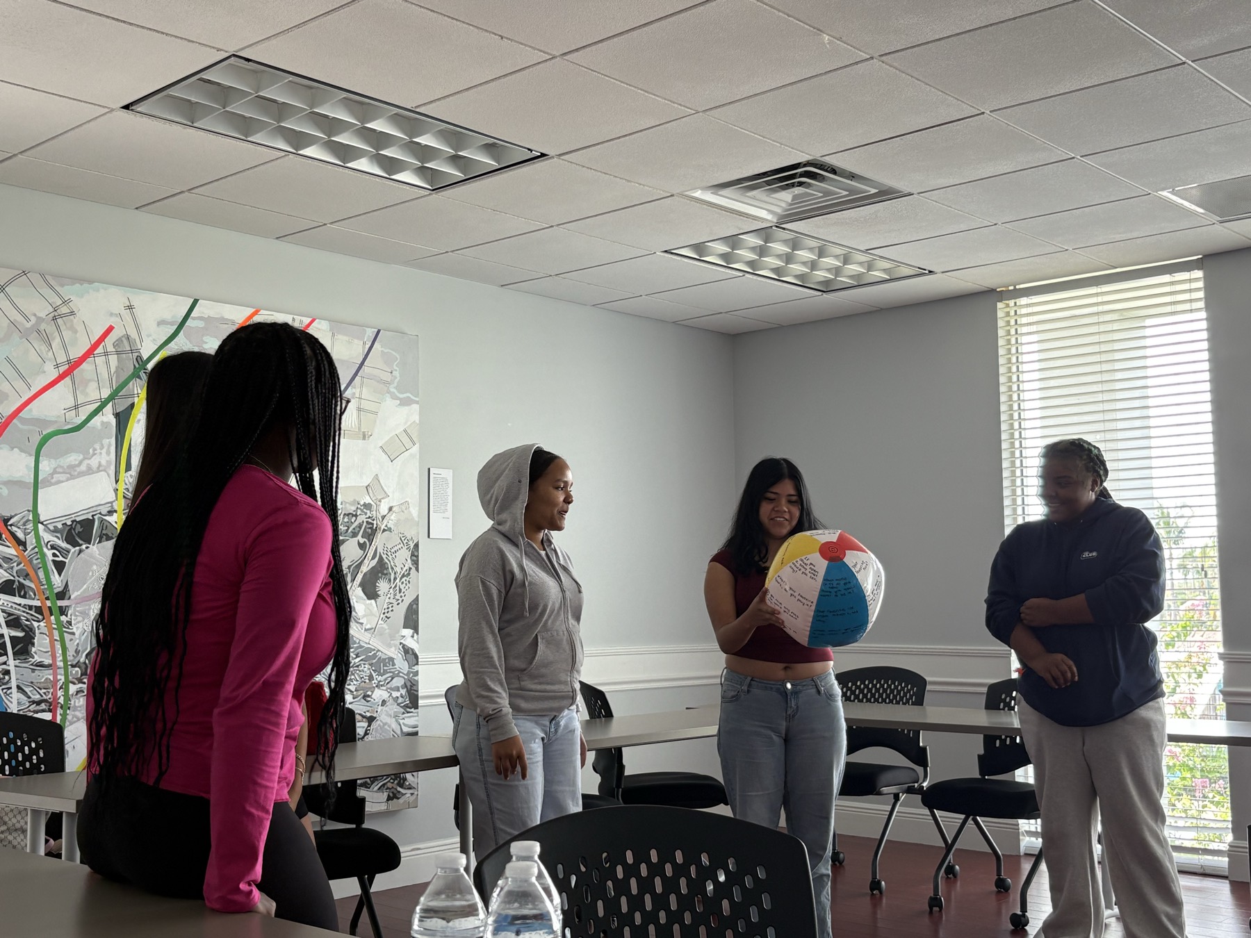 A student holding a beach ball covered in writing while speaking to classmates during an icebreaker activity